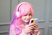 Vanilla Girl. Kawaii vibes. Little girl with pink hair have party. Listening music with headphones, mobile phone.