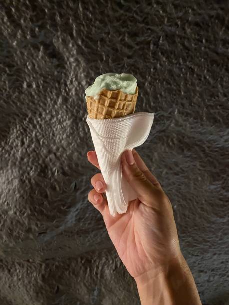 istock Woman's hand with pistachio ice cream horn on dark background 1769333464
