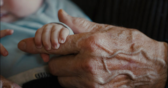 Incredible tenderness in the details,A detailed image capturing the small hand of a baby boy securely holding his grandfather's finger,showcasing a beautiful intergenerational connection