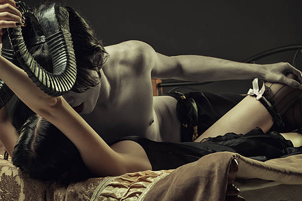 Dark desire of a horned man on top of woman wearing lingerie stock photo