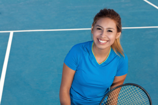 Happy young tennis player on court.