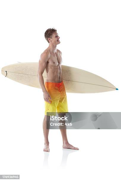Foto de Sorrindo Jovem Surfista Com Prancha De Surfe e mais fotos de stock de 18-19 Anos - 18-19 Anos, Adulto, Atividade Recreativa