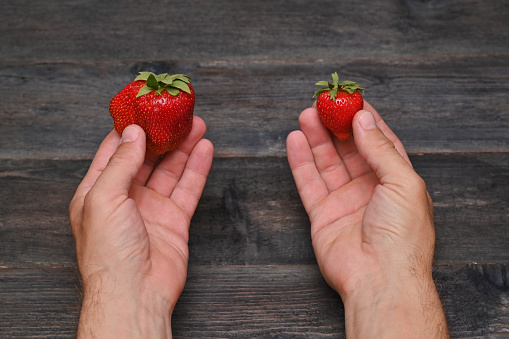 strawberry in hands on natural wooden background.