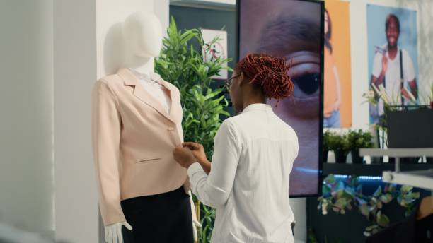 продавщица раскладывает пиджак манекена - department store suit mannequin clothing стоковые фото и изображения