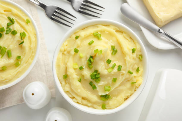 istock Bowls of delicious mashed potato with green onion on white table, flat lay 1769398492