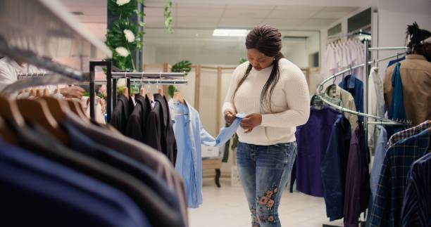 istock Woman closely looking at shirts in mall 1769408880