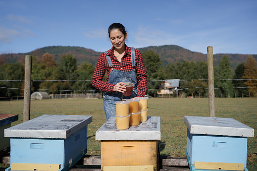 latin woman working on stacking honey jars after harvest
