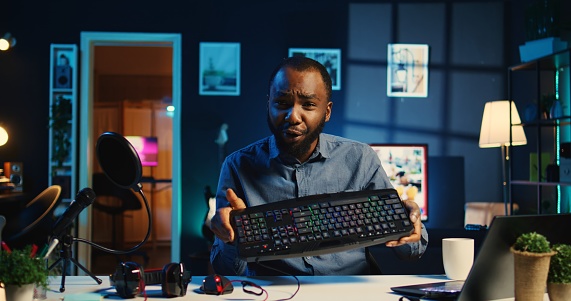 African american technology online star filming review of newly released wired gaming mouse, keyboard and headphones, giving viewership feedback and presenting specifications