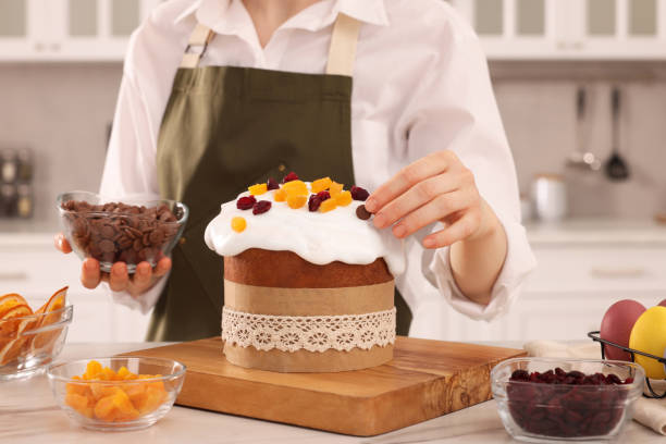 istock Woman decorating delicious Easter cake with chocolate pieces at white marble table in kitchen, closeup 1769491572