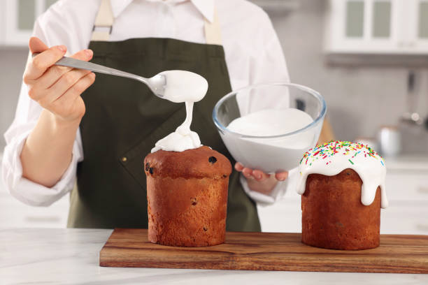 istock Woman decorating traditional Easter cake with glaze at white marble table in kitchen, closeup 1769493778
