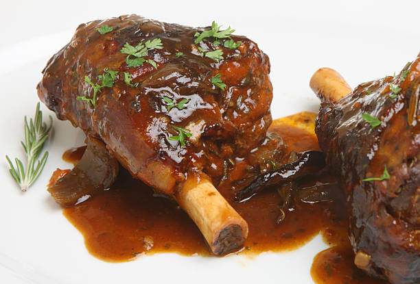 Isolated picture of roasted lamb shanks Lamb shanks roasted with a rich onion gravy. Shallow DoF. braised stock pictures, royalty-free photos & images