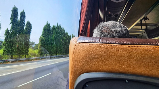 Back view of old man sitting on the seat as bus rider