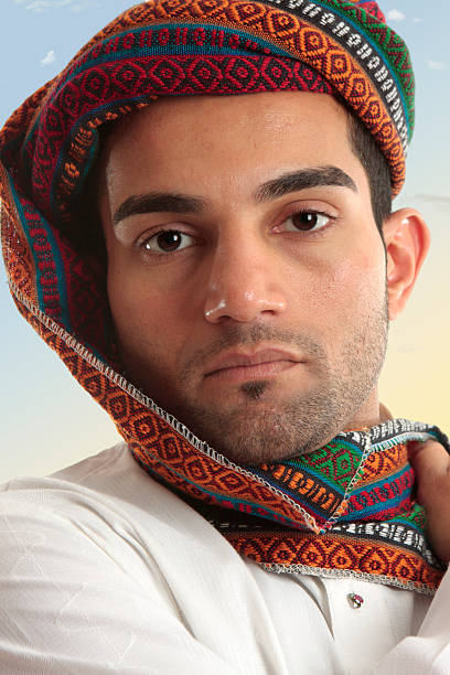 Arab man wearing a colourful wovan keffiyeh or turban style  head piece.  These headdresses serve a purpose of protecting nose and mouth from dust and fierce sand storms as the fabric can be wrapped across the face when needed.