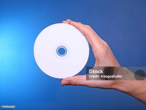 Photo libre de droit de Main Tenant Disque Cd Dvd Sur Fond Bleu banque d'images et plus d'images libres de droit de Blanc - Blanc, Bleu, Cercle