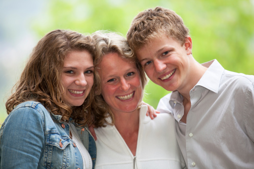 a happy smiling mother with her  teenage daughter and teenage son posing cheek to cheek