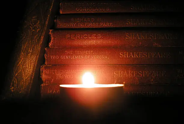 "Some cloth-bound, antique copies of Shakespeare's plays, seen by candlelight."