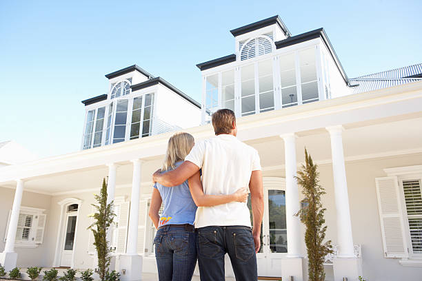Young Couple Standing Outside Dream Home Young Couple Standing Outside Dream Home model home photos stock pictures, royalty-free photos & images