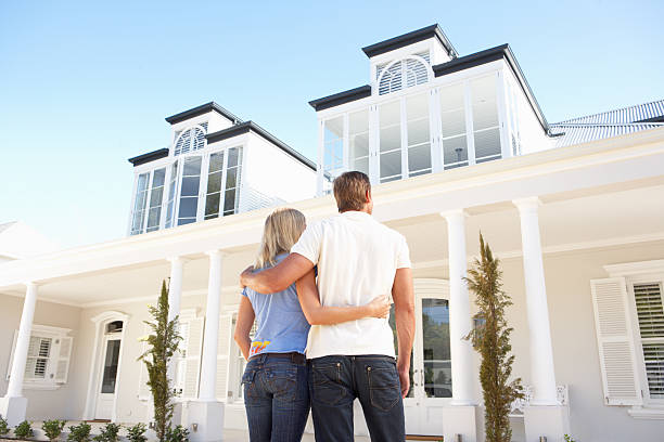 Young Couple Standing Outside Dream Home Young Couple Standing Outside Dream Home show home stock pictures, royalty-free photos & images