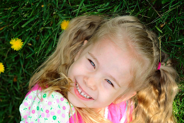 istock smiling little girl lying on grass 176955253