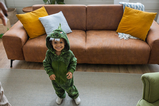 Little child in dragon costume. It is Christmas time and he can't wait to open gifts.