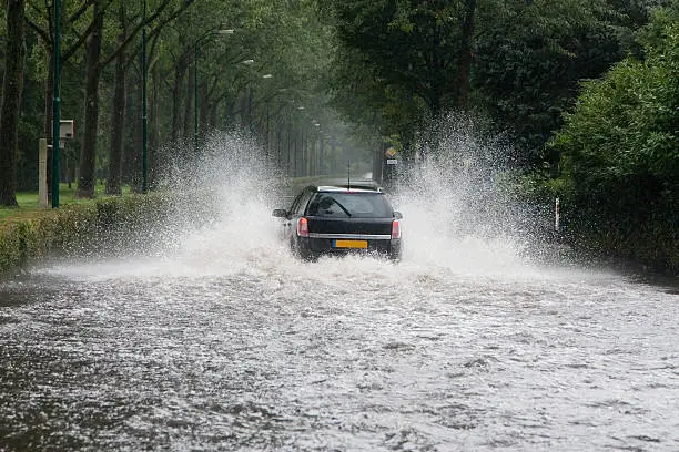 Photo of Car driving through a flooded street
