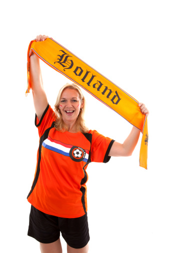 Dutch female soccer supporter in orange outfit holding flag ready for the match over white background