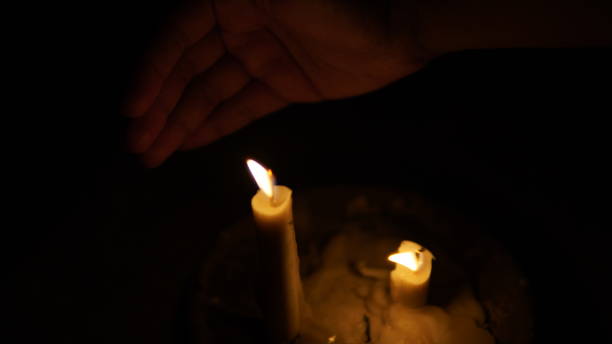 istock a candle flame in the dark and a hand behind it 1769575195