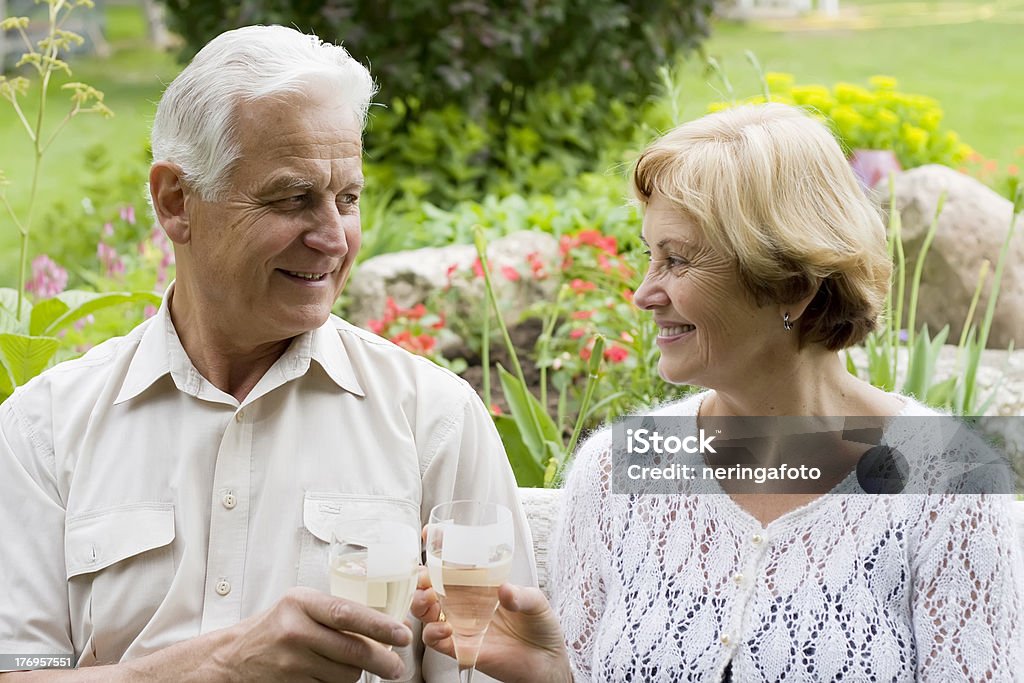 couple âgé buvant du champagne dans un jardin fleuri - Photo de Activité libre de droits