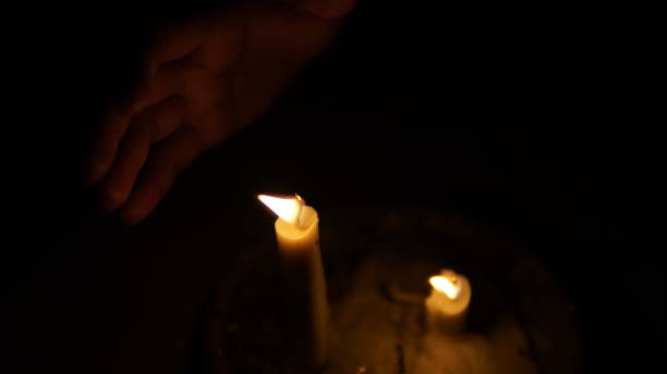 istock a candle flame in the dark and a hand behind it 1769575730