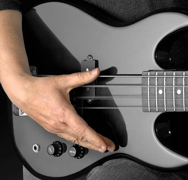 bass guitar and hand detail of a black bass guitar and hand in dark back regler stock pictures, royalty-free photos & images