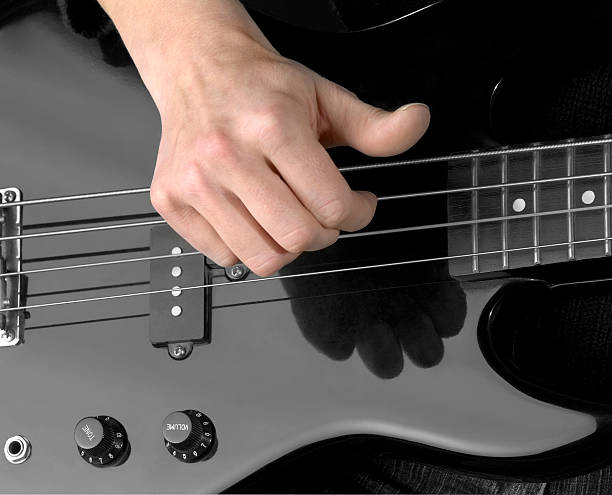 hand and electric bass detail of a black bass guitar and hand in dark back regler stock pictures, royalty-free photos & images