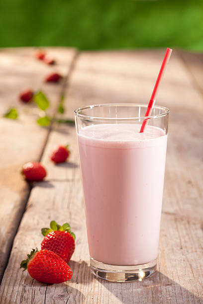 A glass of strawberry milk on a wooden table outside stock photo