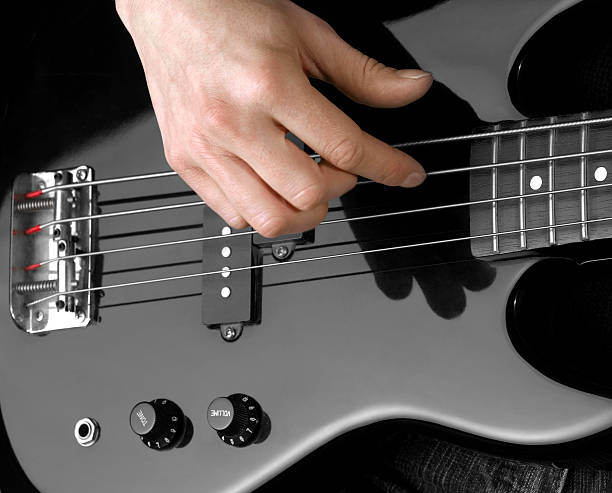 hand on bass guitar female hand on the detail of a black bass guitar in dark back regler stock pictures, royalty-free photos & images