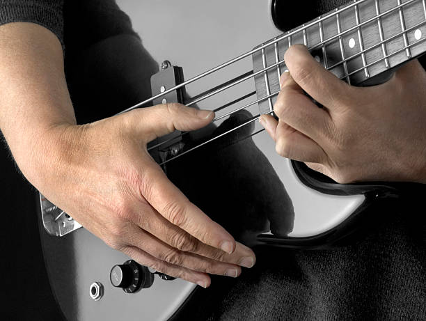 bass playing hands detail of a black bass guitar and hands in dark back regler stock pictures, royalty-free photos & images