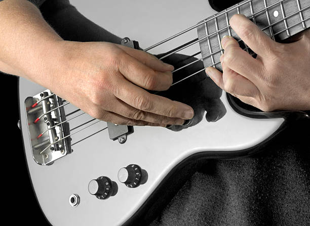 bass guitar playing hands detail of a black bass guitar and hands in dark back regler stock pictures, royalty-free photos & images