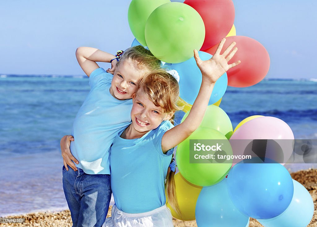 Crianças segurando balões na praia. - Foto de stock de Amarelo royalty-free