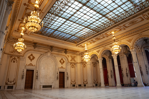 Picture of the interior of the Romanian palace of parliament, with a focus on large wooden doors and chandeliers on a reception hall. The Palace of the Parliament, also known as the Republic's House or People's House/People's Palace, is the seat of the Parliament of Romania, located atop Dealul Spirii in Bucharest, the national capital. The Palace reaches a height of 84 m, has a floor area of 365,000 m² and a volume of 2,550,000 m³.