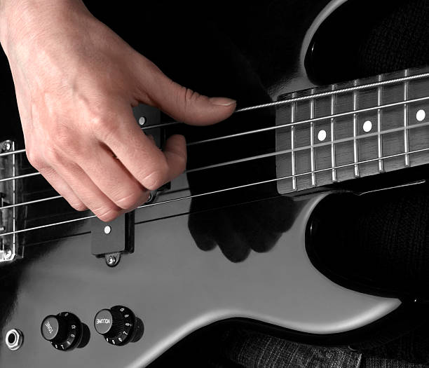 electric bass and hand detail of a black bass guitar and playing hand in dark back regler stock pictures, royalty-free photos & images