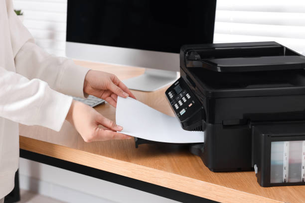 istock Woman loading paper into printer at wooden table indoors, closeup 1769628680