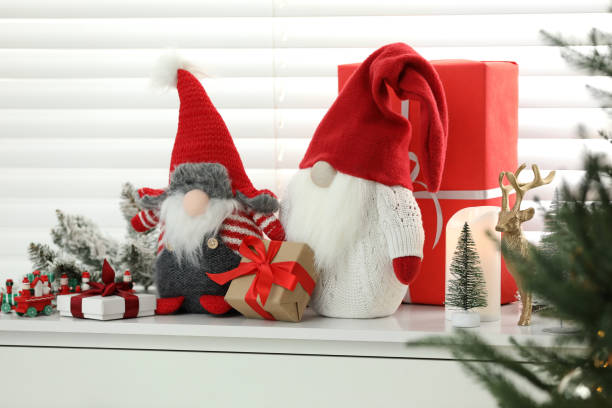 istock Funny Christmas gnomes and gift boxes on commode in room with festive decoration 1769639892