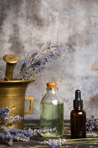 Preparation of lavender for making homemade herbal oil and the finished product in glass bottles. On a gray background