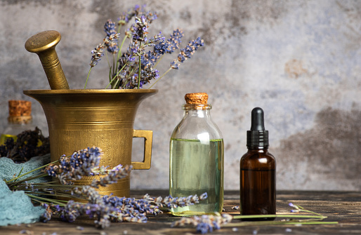 Preparation of lavender for making homemade herbal oil and the finished product in glass bottles. On a gray background