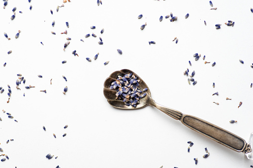 Abstract background with lavender flower heads sprinkled on a white background and in a small spoon