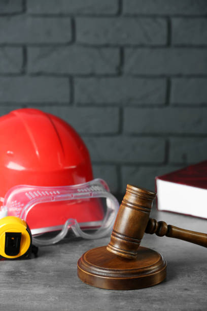 istock Construction and land law concepts. Gavel, hard hat, protective goggles and measuring tape on gray table against brick wall 1769667459