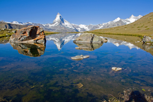 Reflection of the Matterhorn in the Stelisee with two rocks in the foreground