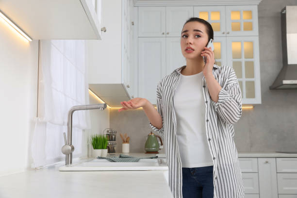 istock Woman talking on phone near sink in kitchen 1769708394