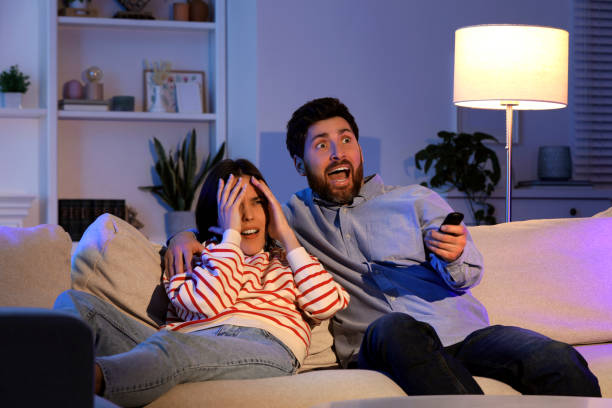 istock Frightened couple watching TV on sofa at home 1769734629