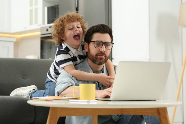 istock Man with laptop working remotely at home. Father and son at desk 1769736245