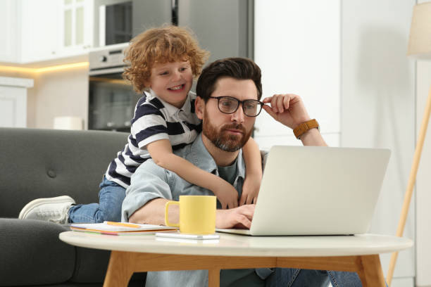 istock Man with laptop working remotely at home. Father and son at desk 1769737947