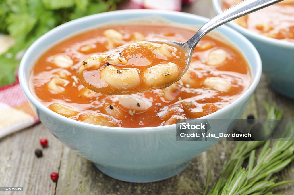 Uma colher de sopa de tomate com massa, feijão-branco e alecrim - Foto de stock de Alecrim royalty-free